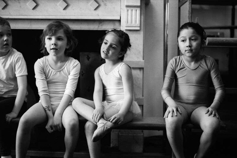 Children waiting on a bench before a ballet class