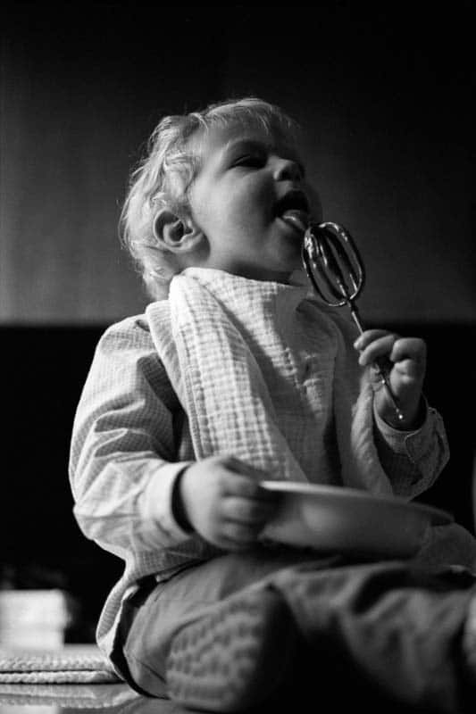 Photo en noir et blanc d'un enfant qui lèche du chocolat faite par un photographe à Bruxelles