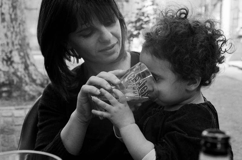 Une maman fait boire un grand verre d'eau à son enfant