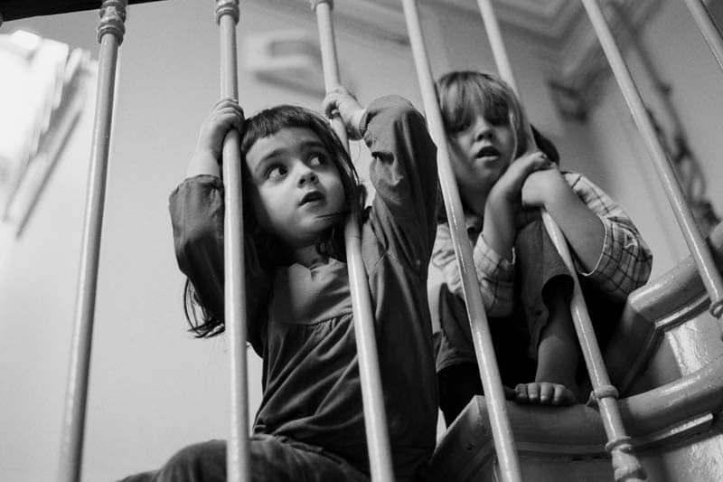 Photo en noir et blanc de deux enfants dans l'escalier