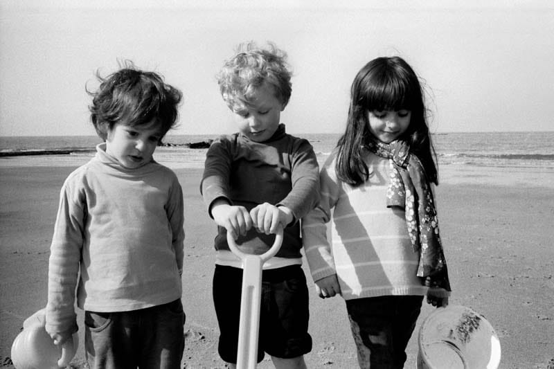 Black and white photo of two boys and a girl at the sea