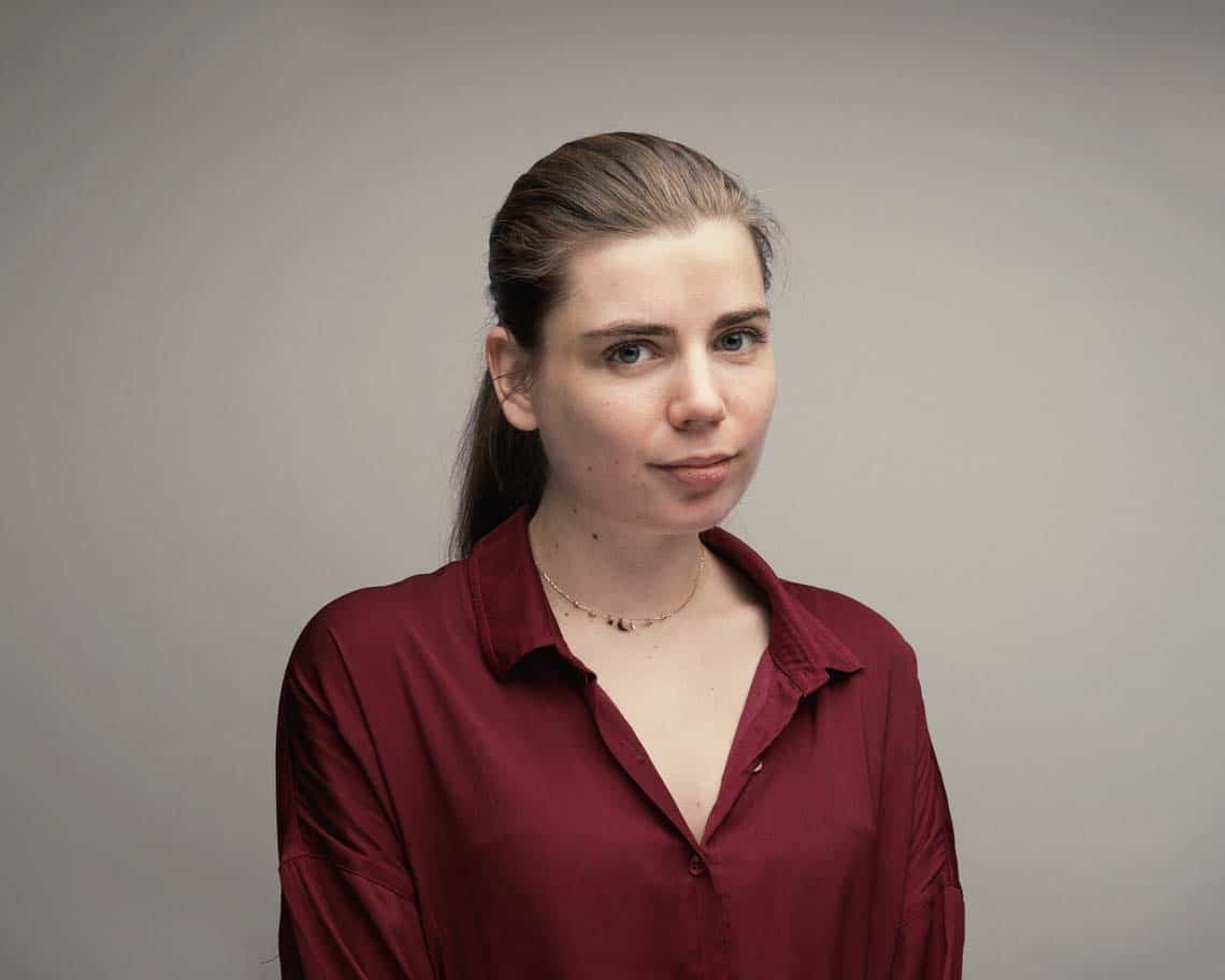 A woman wearing a red shirt poses for a studio professional portrait
