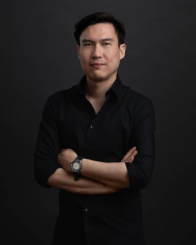 Portrait corporate d'un homme portrait une chemise noire, sur fond sombre en studio à Bruxelles
