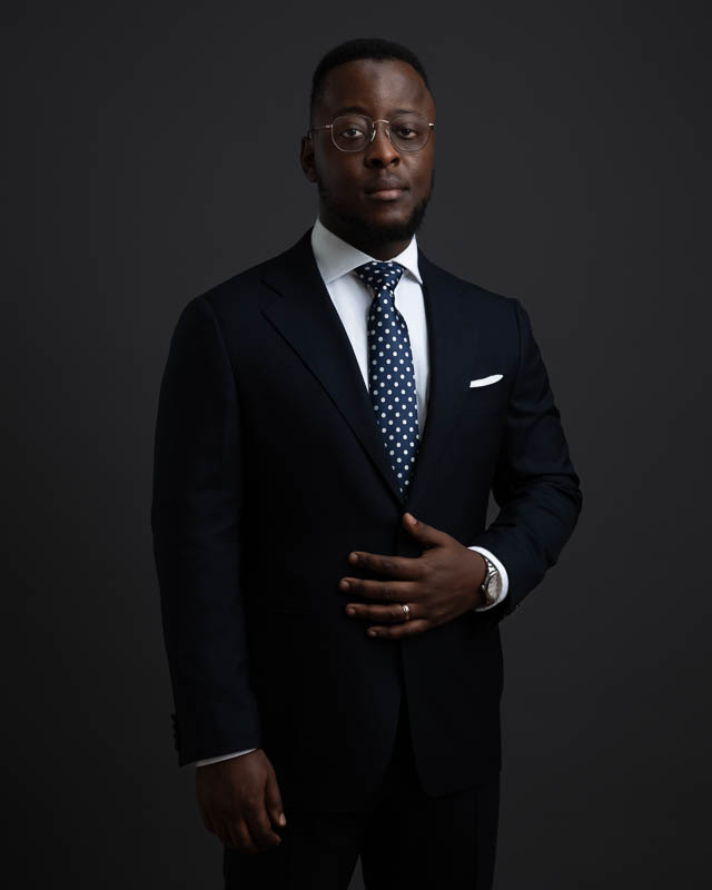 Portrait d'un homme noir portant des lunettes posant devant un fond anthracite en studio